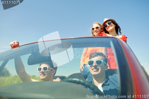 Image of happy friends driving in cabriolet car