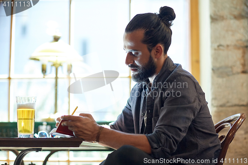 Image of close up of man with beer and notebook at pub