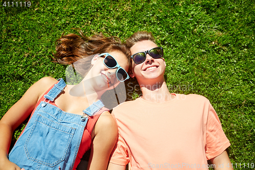 Image of happy teenage couple lying on grass at summer