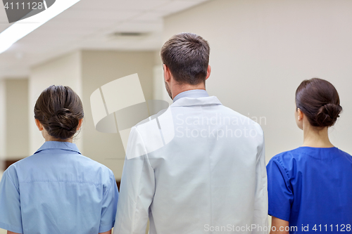 Image of group of medics or doctors walking along hospital