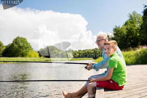 Image of grandfather and grandson fishing on river berth