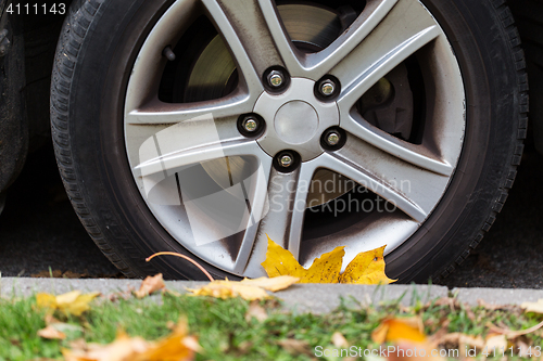 Image of close up of car wheel and autumn leaves