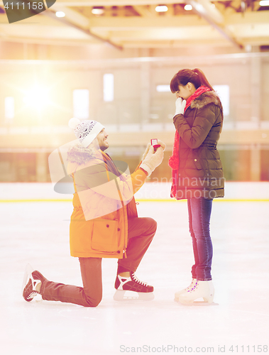 Image of happy couple with engagement ring on skating rink