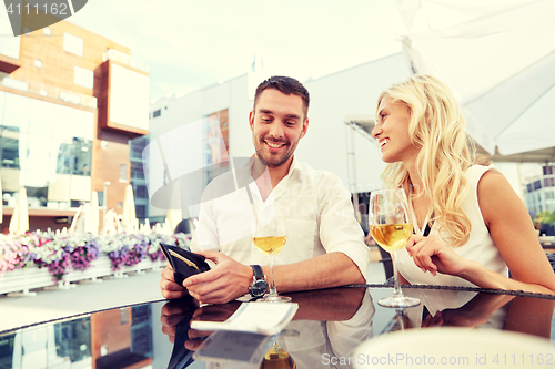 Image of happy couple with wallet paying bill at restaurant