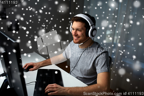 Image of man in headset playing computer video game at home