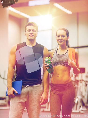 Image of happy couple in gym with water and tablet pc