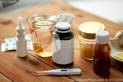 Image of drugs, thermometer, honey and cup of tea on wood