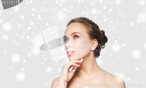 Image of beautiful young woman touching her face over snow