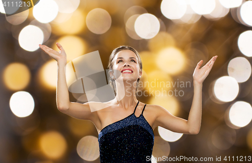 Image of smiling woman raising hands and looking up