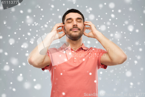 Image of happy man listening to music over snow background