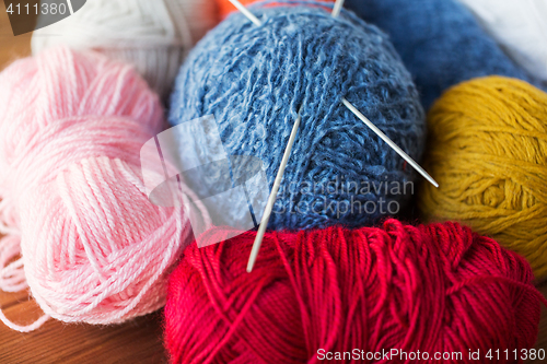 Image of knitting needles and balls of yarn on wood