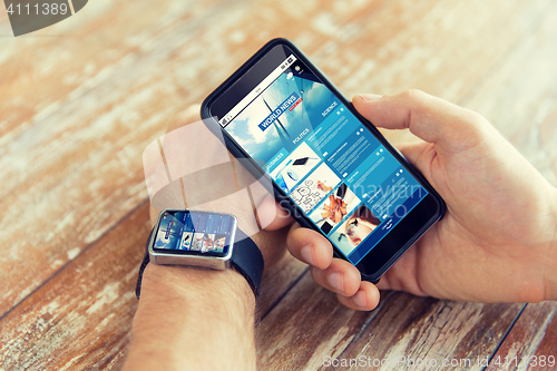 Image of hands with news web page on smart phone and watch