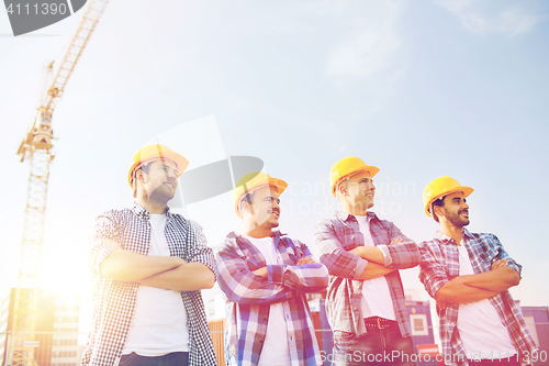 Image of group of smiling builders in hardhats outdoors