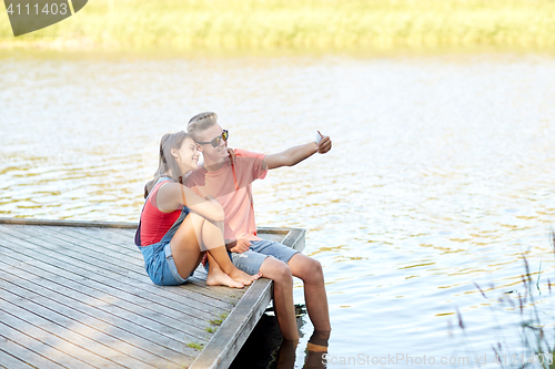 Image of happy teenage couple taking selfie on smartphone