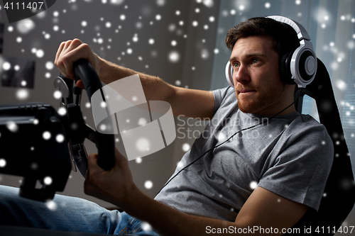 Image of man playing car racing video game at home