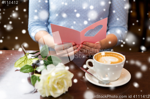 Image of woman with coffee and flower reading greeting card