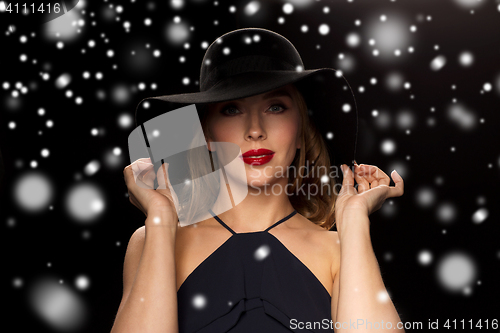 Image of beautiful woman in black hat over snow