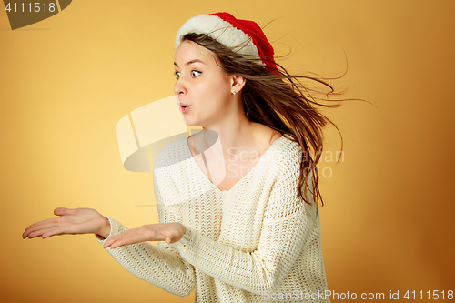 Image of Surprised christmas girl wearing a santa hat