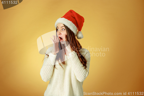 Image of Surprised christmas girl wearing a santa hat