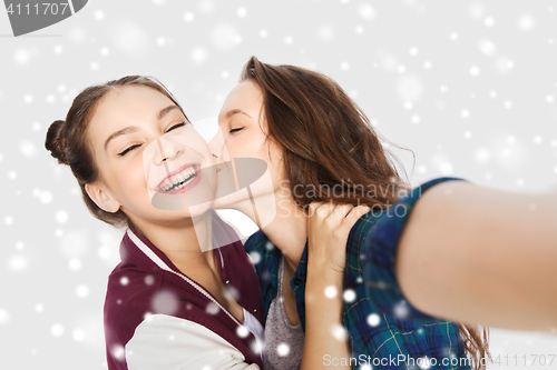 Image of happy teenage girls taking selfie and kissing