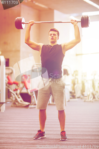 Image of young man flexing muscles with barbell in gym