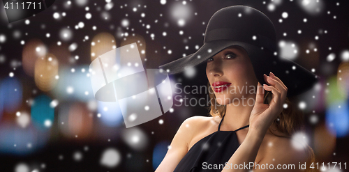 Image of beautiful woman in black hat over night lights