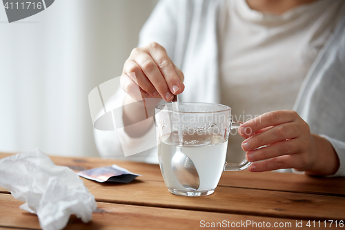 Image of woman stirring medication in cup with spoon