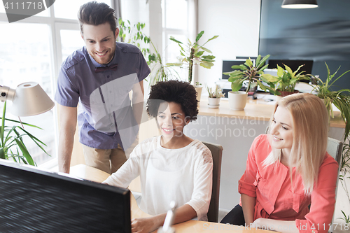 Image of happy creative team with computer in office