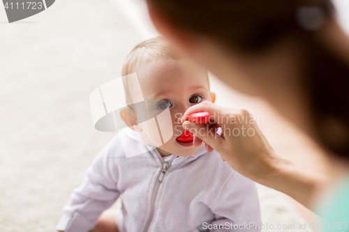 Image of mother with spoon feeding little baby at home