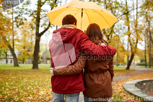 Image of happy couple with umbrella walking in autumn park