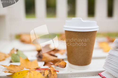 Image of coffee drink in paper cup on bench at autumn park