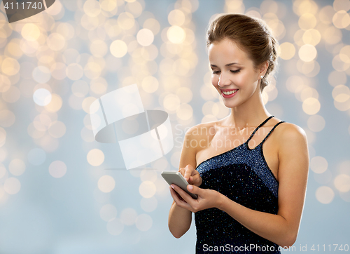 Image of smiling woman in evening dress with smartphone