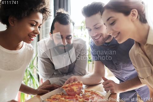 Image of happy business team eating pizza in office