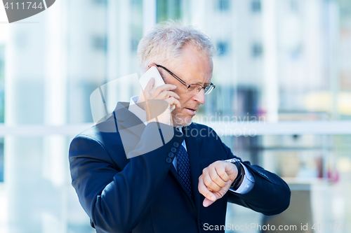 Image of senior businessman calling on smartphone in city