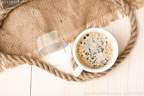 Image of Cup of coffee with foam on wooden table