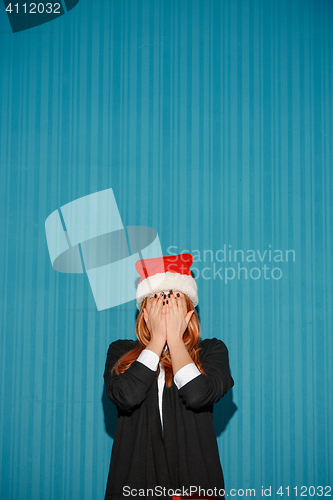 Image of Surprised christmas girl wearing a santa hat