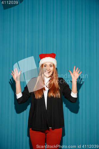 Image of Surprised christmas girl wearing a santa hat