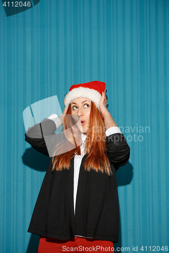 Image of Surprised christmas girl wearing a santa hat