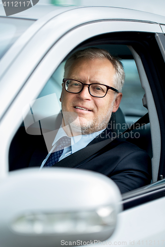 Image of happy senior businessman driving car