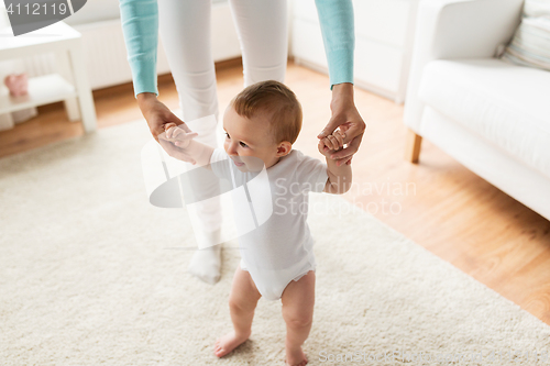 Image of happy baby learning to walk with mother help