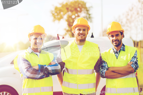 Image of group of smiling builders in hardhats outdoors