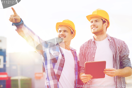 Image of smiling builders in hardhats with tablet pc