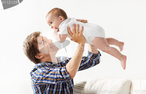 Image of happy young father playing with baby at home