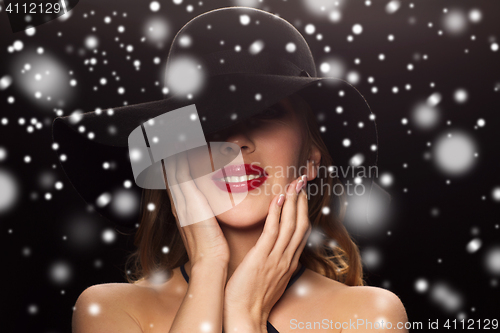 Image of beautiful woman in black hat over snow