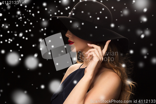 Image of beautiful woman in black hat over snow