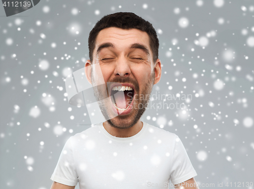 Image of crazy shouting man in t-shirt over snow background