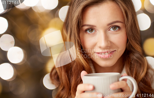 Image of close up of happy woman with tea cup over lights