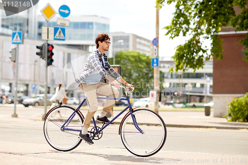 Image of young hipster man with bag riding fixed gear bike