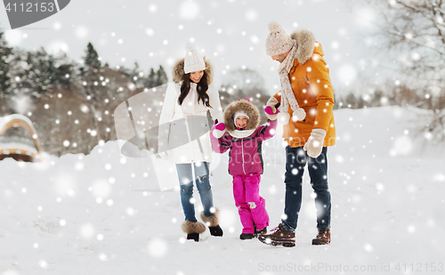 Image of happy family in winter clothes walking outdoors