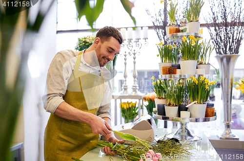 Image of smiling florist man making bunch at flower shop